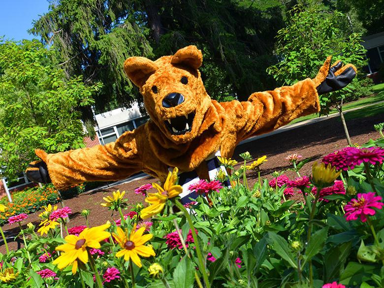 The Nittany Lion standing behind some flowers